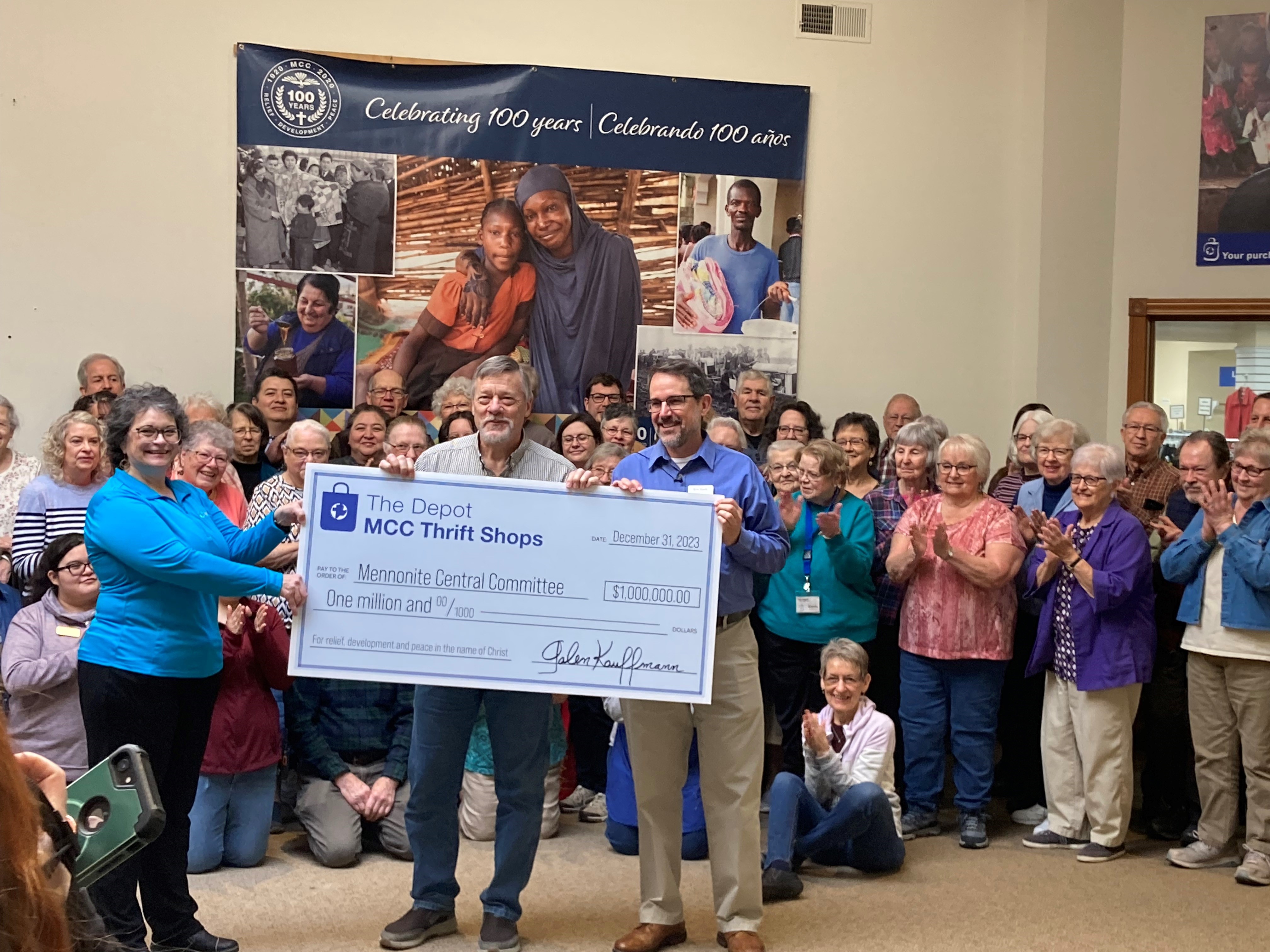 three people hold large check for $1 million while crowd looks on